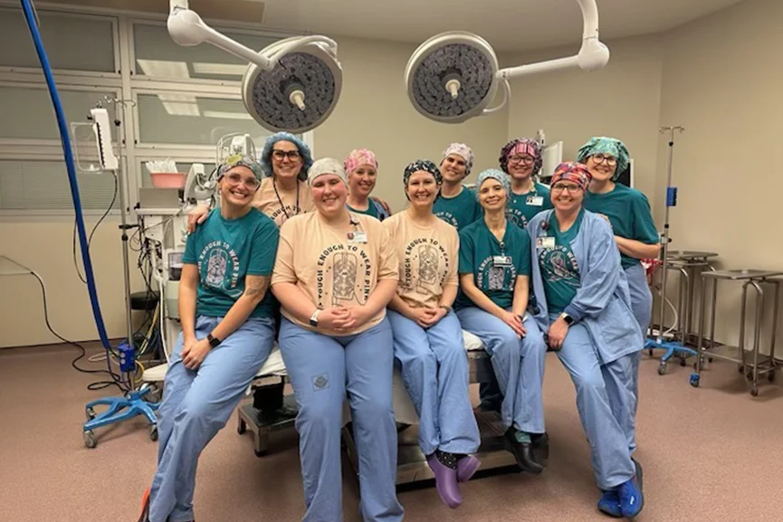 Surgical team posing together inside a hospital operating room.