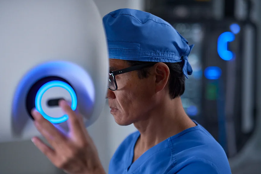 Surgeon operating a robotic-assisted surgery system in the operating room.